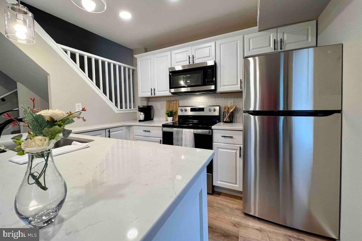 a kitchen with stainless steel appliances a refrigerator a microwave a stove and white cabinets