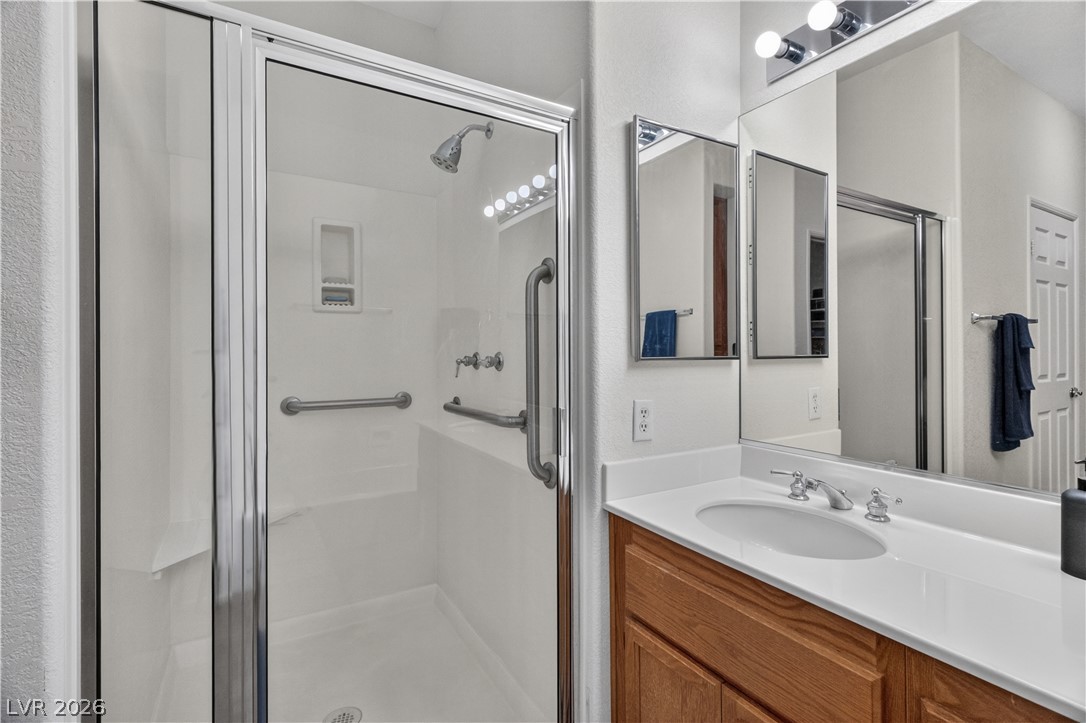3376 Partridge Run Street Laughlin, NV 89029 - Photo 35 of 92 A well-appointed bathroom features a glass-enclosed shower alongside a vanity with a single sink and expansive mirror.