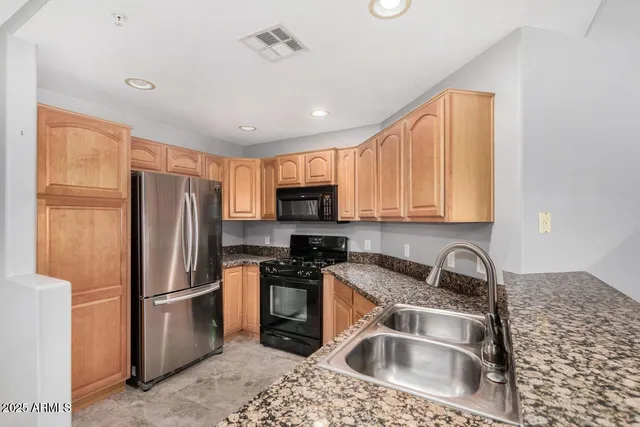 a kitchen with stainless steel appliances granite countertop a refrigerator sink and stove