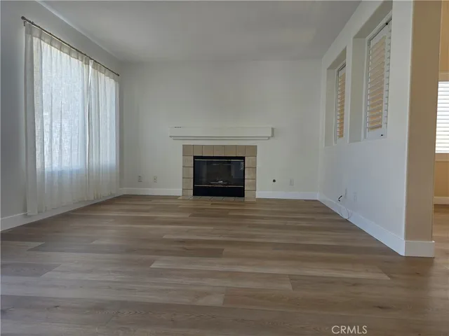 a view of empty room with wooden floor and fireplace
