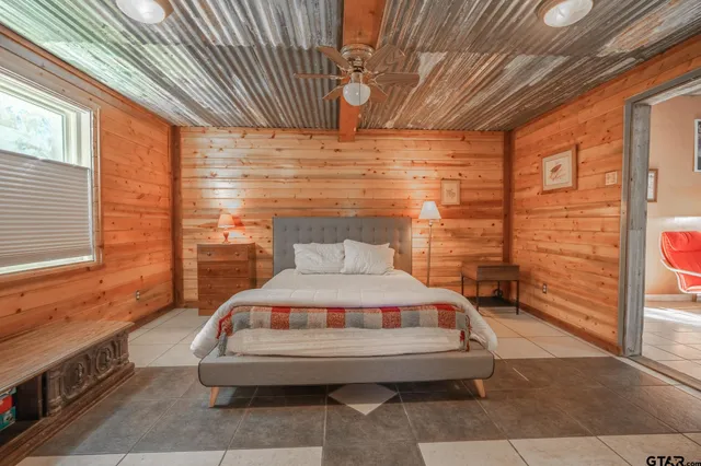 a bedroom with a bed a dresser and next to a window