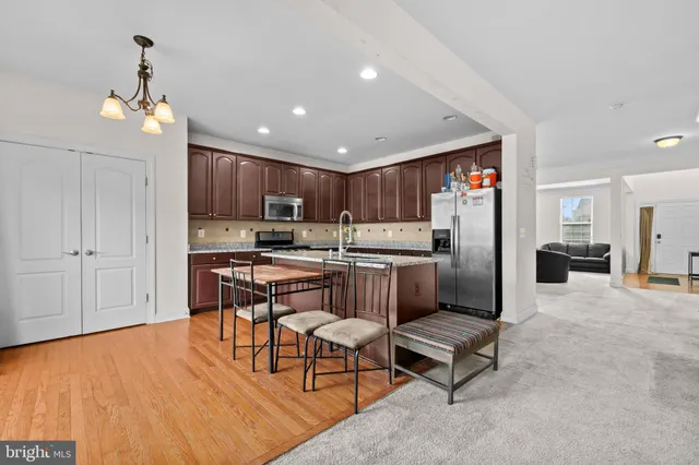 a kitchen with stainless steel appliances kitchen island granite countertop a refrigerator a stove a sink dishwasher and white cabinets with wooden floor