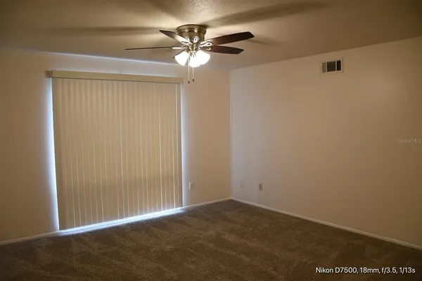an empty room with a ceiling fan and a window