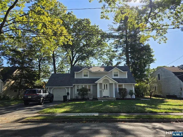 a front view of a house with a garden and trees