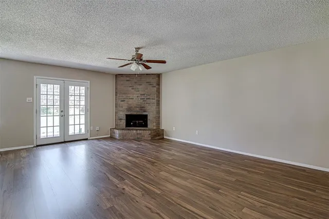 a view of an empty room with wooden floor and a fireplace