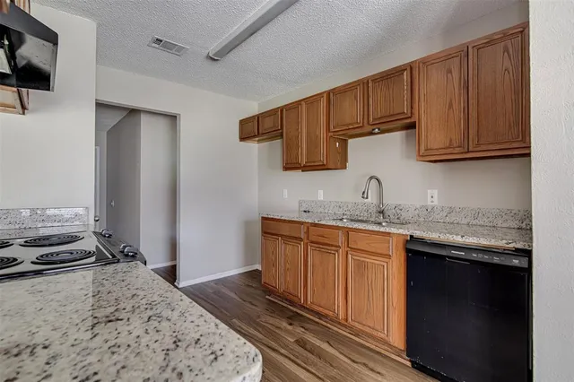 a kitchen with granite countertop a sink stove and cabinets