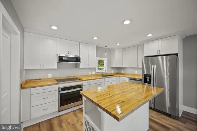 a kitchen with a refrigerator a sink and white cabinets