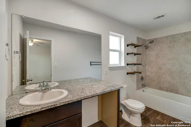 a bathroom with a granite countertop sink toilet mirror and bathtub