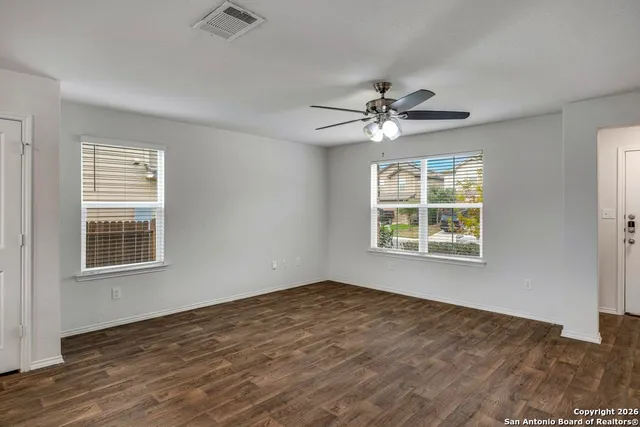 a view of an empty room with a window and a chandelier fan