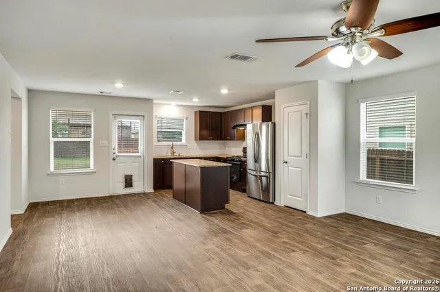 a view of an empty room with a kitchen and wooden floor