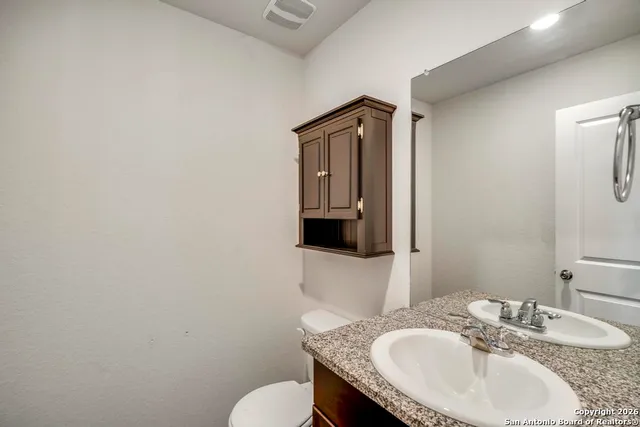 a bathroom with a granite countertop sink toilet and mirror