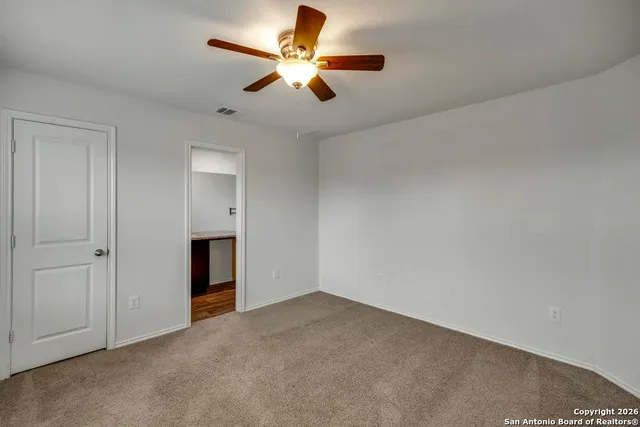 an empty room with closet and a ceiling fan