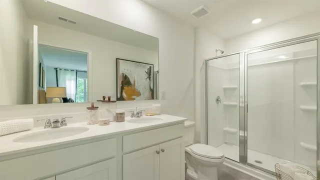 a bathroom with a shower sink vanity mirror and toilet