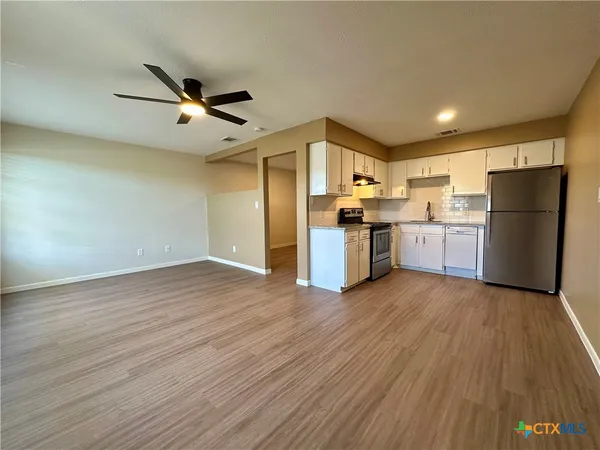 a view of kitchen with cabinets appliances wooden floor and window