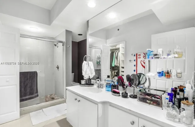 a view of bathroom with sink mirror and shower