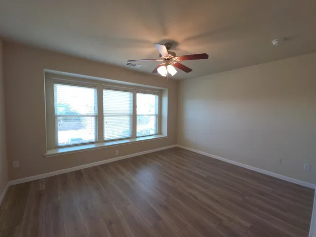 a view of an empty room with a window and wooden floor