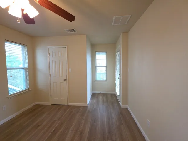 a view of an empty room with wooden floor and a window