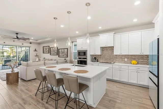 a kitchen with stainless steel appliances kitchen island granite countertop a stove a sink a dining table and chairs