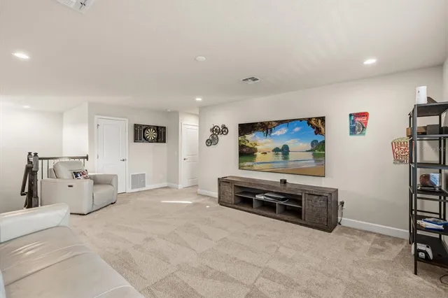 a living room with furniture a flat screen tv and a refrigerator