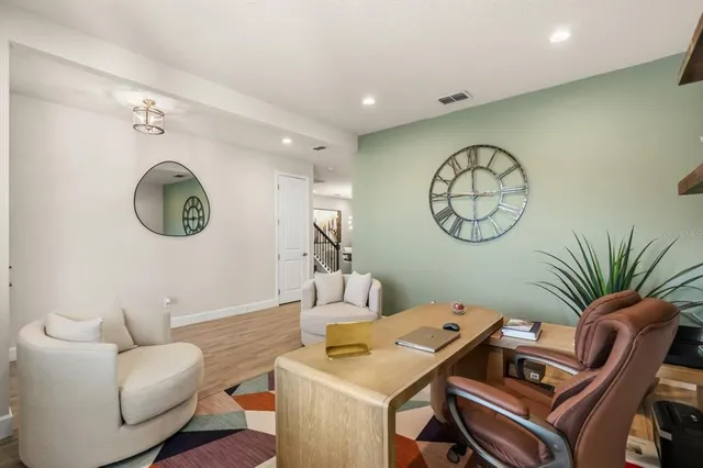a living room with furniture a clock and a view of a kitchen