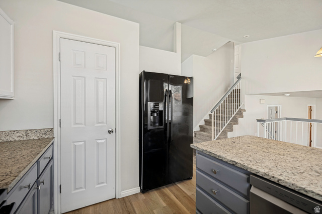 5529 Ridge Hollow Way Kearns, UT 84118 - Photo 8 of 23 Kitchen area featuring wood-finish flooring, a black side-by-side refrigerator, and light-colored granite-style countertops