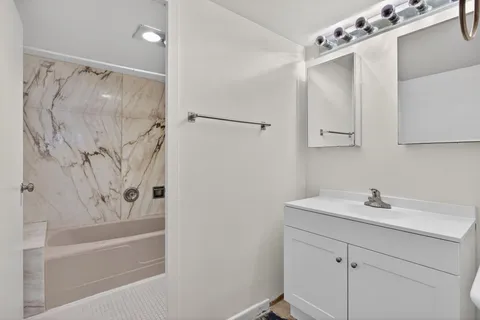 a bathroom with a sink a mirror a shower and a bathtub