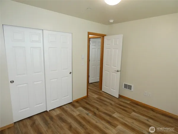 an empty room with wooden floor and closet area