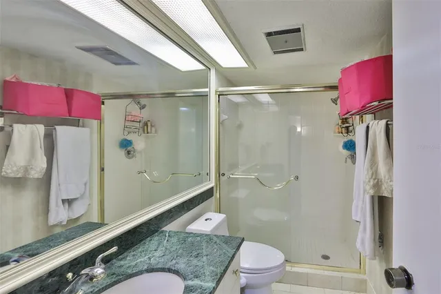 a bathroom with a granite countertop bathtub shower sink vanity and toilet