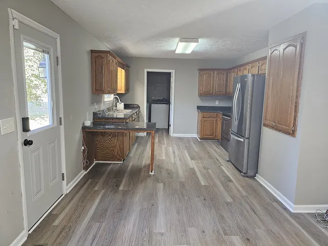 a view of a kitchen with wooden floor electronic appliances and windows