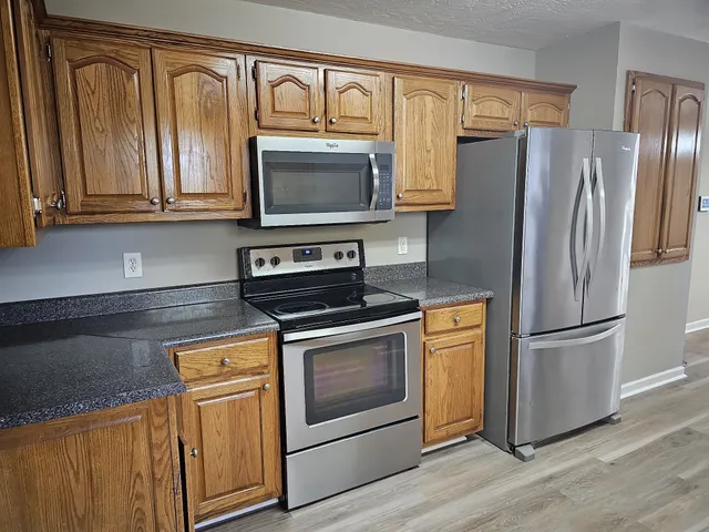 a kitchen with stainless steel appliances granite countertop a refrigerator stove and microwave