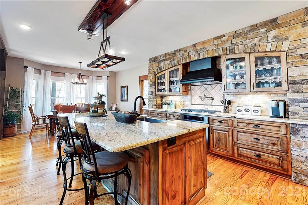 7555 Stokes Ferry Road Salisbury, NC 28146 - Photo 13 of 48 a kitchen with stainless steel appliances granite countertop a sink dishwasher a dining table and chairs with wooden floor