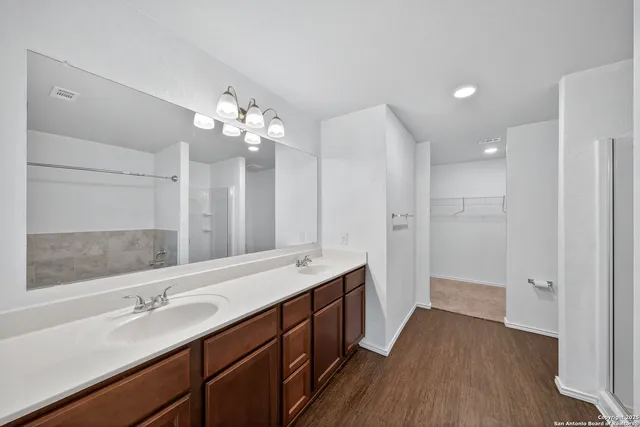 a bathroom with a double vanity sink a large mirror a shower and a bathtub