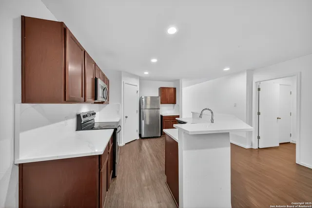 a view of a kitchen island a sink wooden floor and a living room