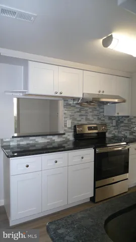 a kitchen with granite countertop a stove and white cabinets