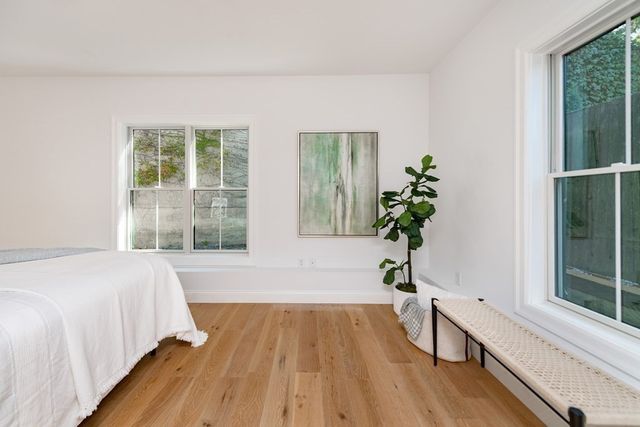 a bedroom with a bed and a large window with wooden floor