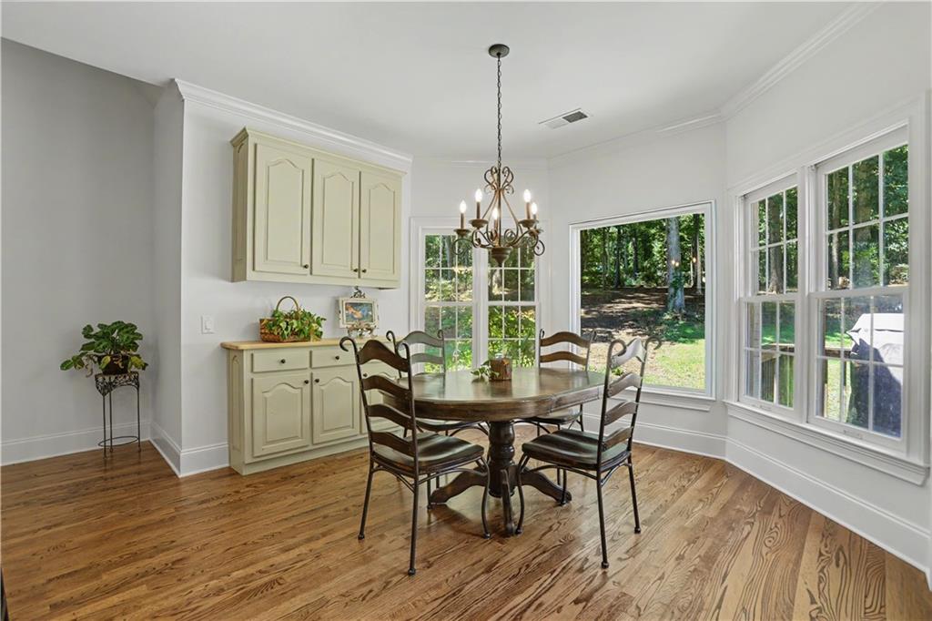 537 Old Collins Road Hoschton, GA 30548 - Photo 16 of 42 a dining room with furniture potted plants and wooden floor