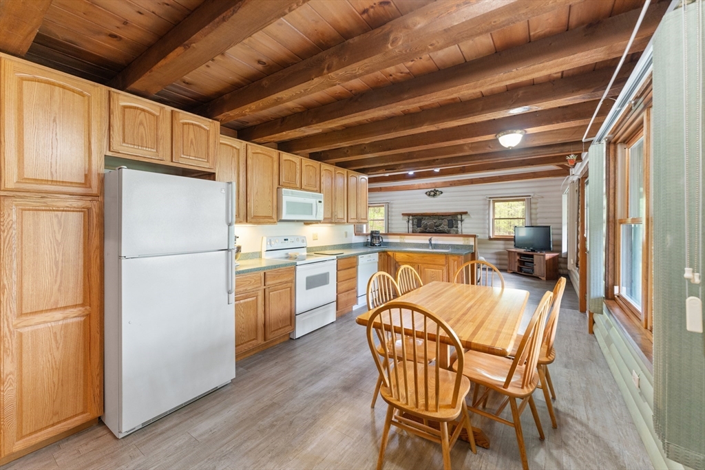 470 Mountain Road Wilbraham, MA 01095 - Photo 16 of 42 a kitchen with a refrigerator a microwave oven a stove and a dining table with wooden floor