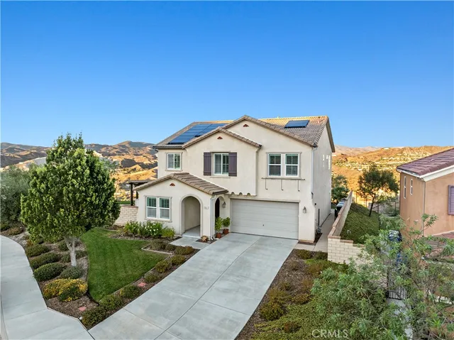 a view of a white house with a small yard and a large tree