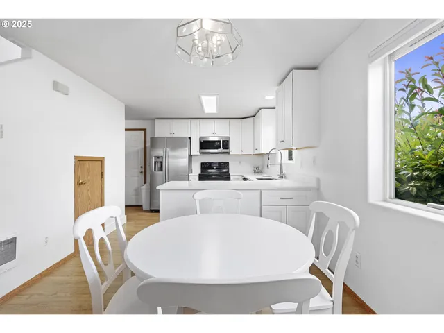 a living room with stainless steel appliances furniture a dining table and a window