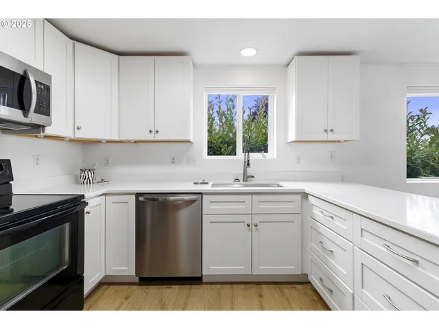 a kitchen with stainless steel appliances kitchen island white cabinets granite counter tops and a window