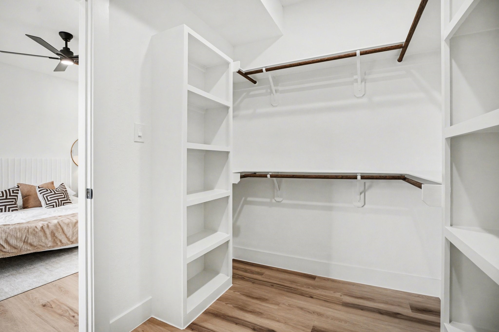 115 Milby Street Houston, TX 77003 - Photo 17 of 28 This photo shows a spacious walk-in closet with white shelving and wooden rods for hanging clothes.