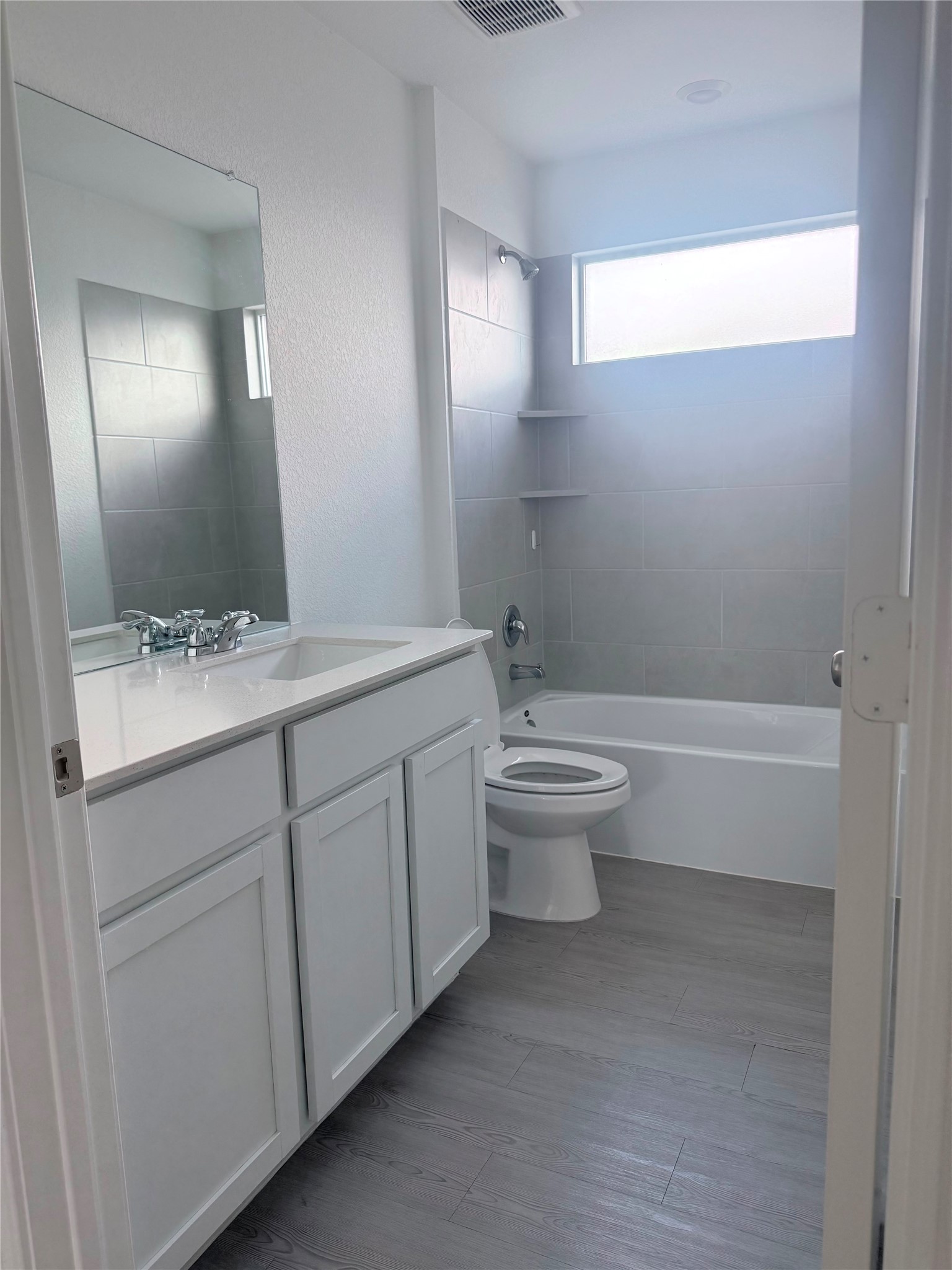 192 Rodney Boat Road Kyle, TX 78640 - Photo 20 of 40 A well-appointed bathroom features a spacious vanity and sleek gray tile work.