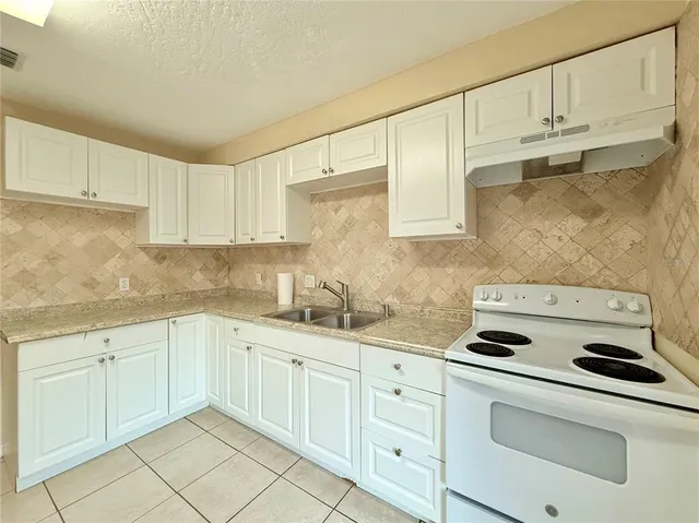 a kitchen with granite countertop white cabinets white stainless steel appliances and sink