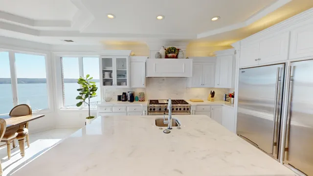 a kitchen with stainless steel appliances granite countertop a refrigerator a sink a stove and white cabinets