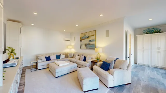 a living room with furniture kitchen view and a wooden floor