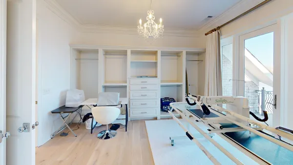 a spacious bedroom with a bed a chandelier and mirror