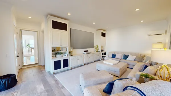 a living room with furniture kitchen view and a wooden floor