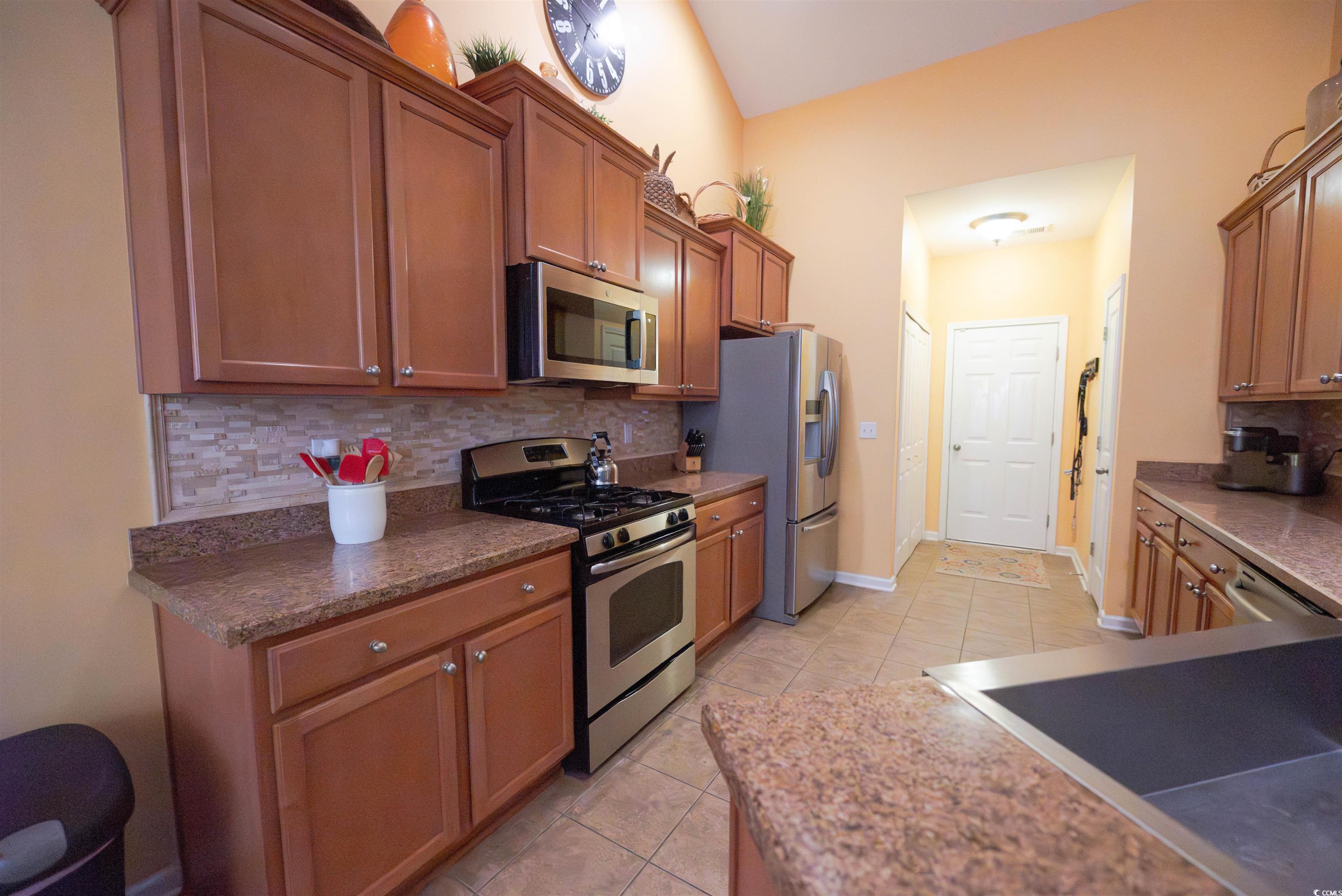 209 Golden Oaks Drive Murrells Inlet, SC 29576 - Photo 15 of 40 Kitchen with tasteful backsplash, appliances with stainless steel finishes, light tile patterned flooring, and brown cabinets