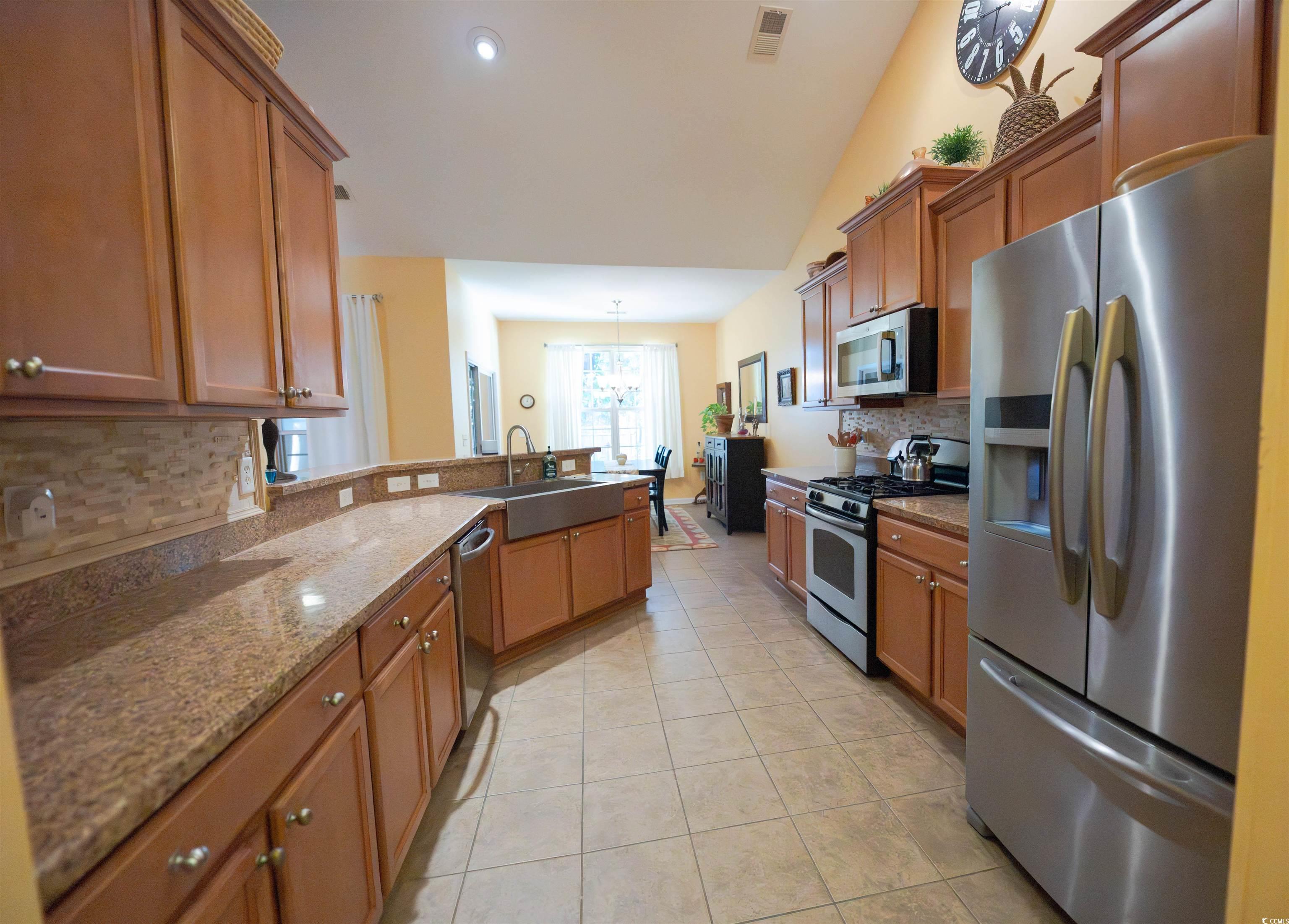 209 Golden Oaks Drive Murrells Inlet, SC 29576 - Photo 16 of 40 Kitchen featuring tasteful backsplash, appliances with stainless steel finishes, light stone countertops, lofted ceiling, and a peninsula