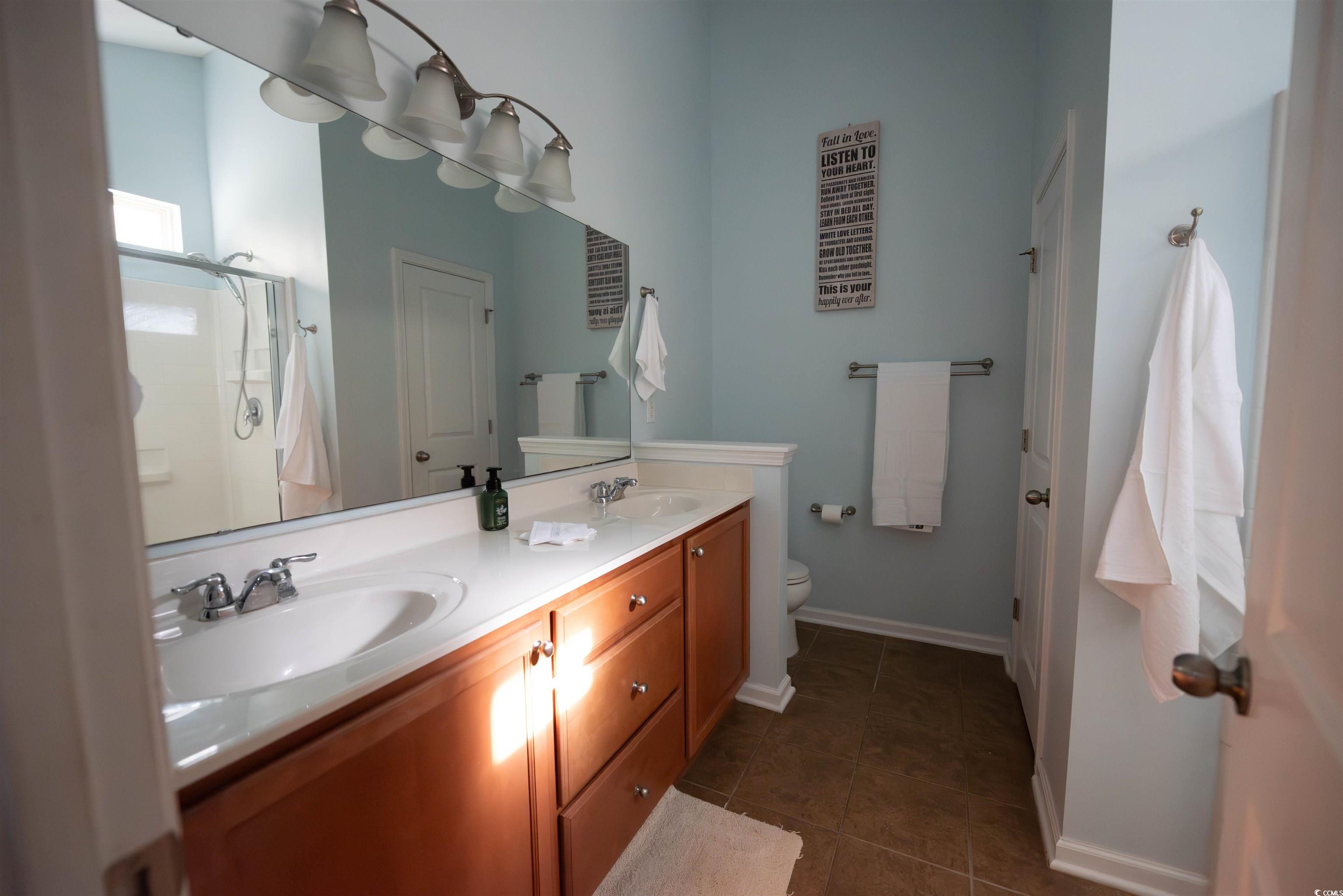 209 Golden Oaks Drive Murrells Inlet, SC 29576 - Photo 20 of 40 Bathroom featuring double vanity, dark tile patterned flooring, and a shower stall